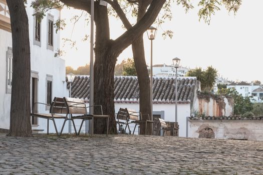 small typical portugal square with its public benches in the shade of the trees