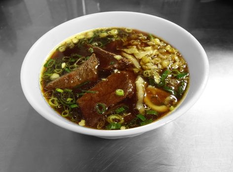 Braised beef in broth with thick noodles and chives is a popular dish in Taiwan