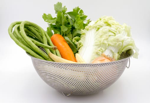 Various types of vegetables in aluminium basket on white background.