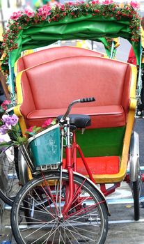 Two traditional cycle rickshaws or pedicabs are parked by the side of the road in Taiwan
