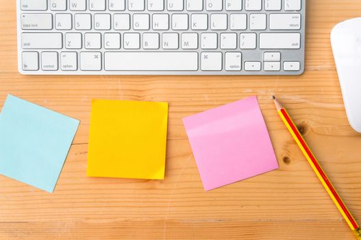 Top view workspace with colorful sticky notes ,pencil, keyboard and mouse on wooden table background.