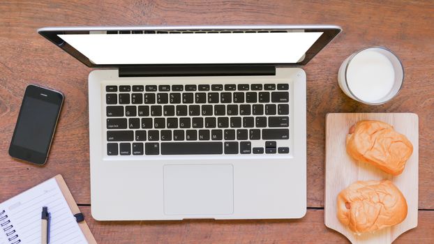 Labtop,notebook,
mobile phone and breakfast on wooden table background.