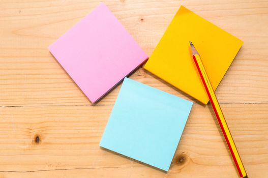 colorful sticky notes with pencil on wooden table background.