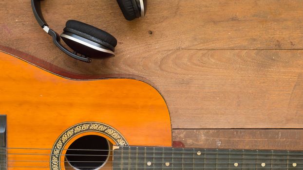 Top view workspace with headphone and acoustic guitar on wooden table background .Free space for your text.
