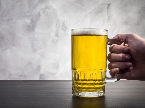 Hand Holding Glass of beer on a grunge background.