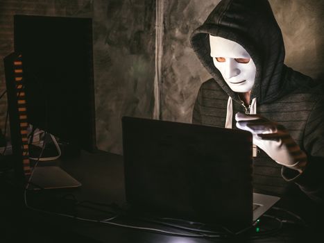 Computer hacker - Man in hoodie shirt with mask stealing data from laptop