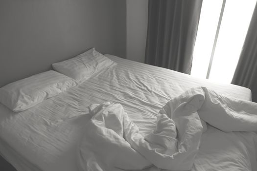 Messy white bedding sheets and pillows. black and white tone