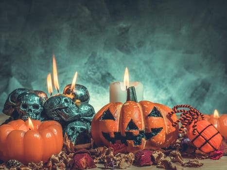 Halloween pumpkins with candlelight and skulls on dark background.Vintage tone