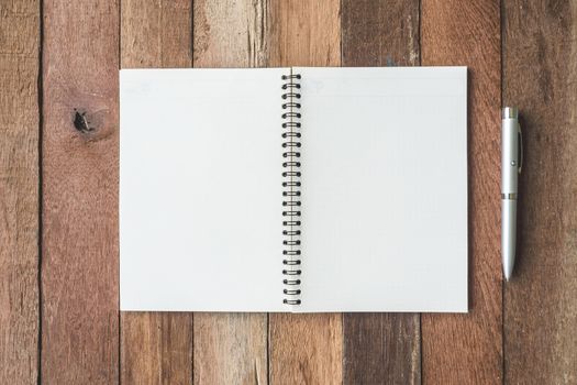 Top view of Blank notebook with pen on wooden table background.