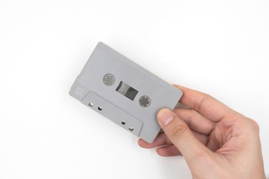 Hand holding cassette tape on white background.