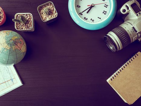 Top view of camera with cactus,map,globe,clock and notebook on the office desk.Vintage tone