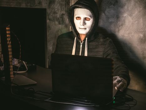 Computer hacker - Man in hoodie shirt with mask stealing data from laptop