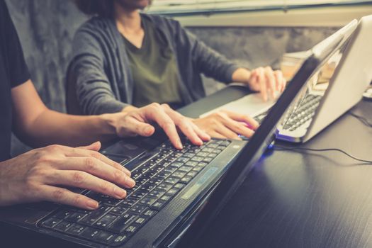 Business partners working together on the same desk, they are using a laptop, Vintage tone