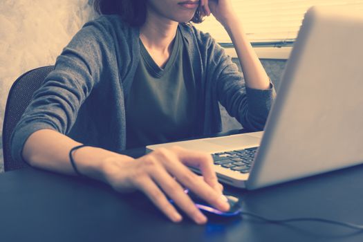 Close up of Casual young woman using a laptop on the desk. Vintage tone