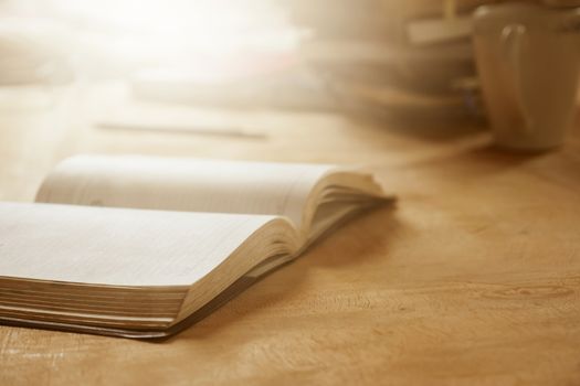 Close up of open notebook on wooden desk, Soft focus, Flare sunlight, Vintage tone.