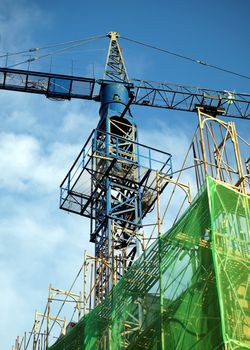 Apartment construction site with a blue crane and green safety netting
