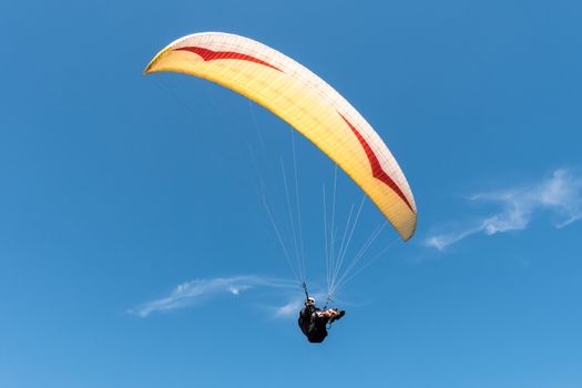 Paraglider flying in blue sky.