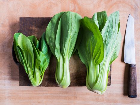 Top view of Bok choy (chinese cabbage) on wooden chopping block with knife.