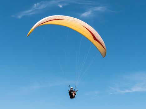 Paraglider flying in blue sky.