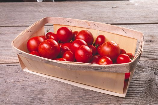 ripe tomatoes in a small wooden crate in studio