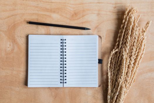 Top view of  notepad with wheat ears on wooden table background.