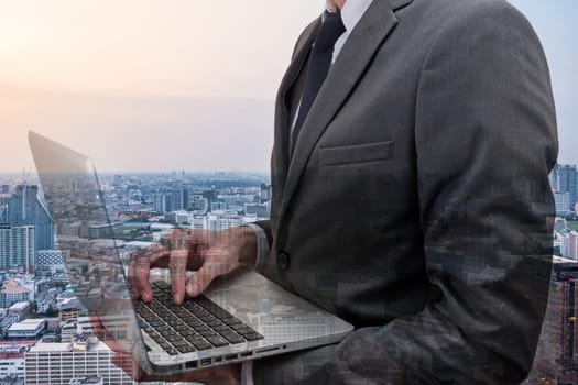 Double exposed of  Businessman holding laptop with cityscape.