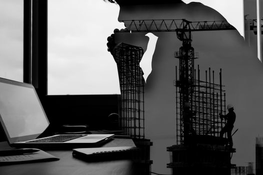 Double exposed of businessman looking at his laptop with the building construction site.