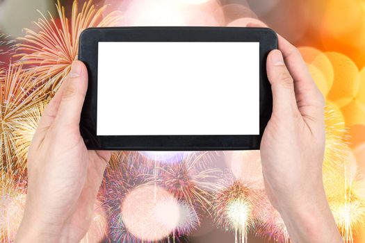 Male hand holding a tablet touch computer gadget with touch blank screen on firework and bokeh lights background.
