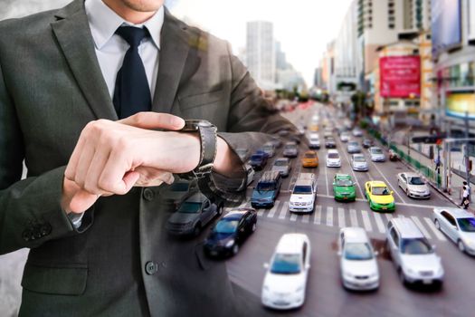 Double exposed of businessman checking time on his wrist watch with traffic jam in the city