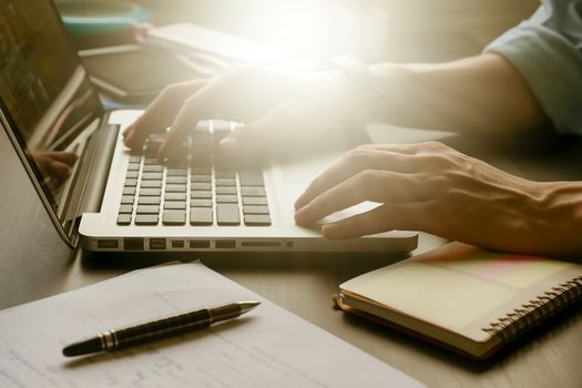 Close up of male hands working on laptop on his office desk,toned with sunlight.