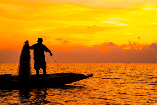 Silhouette of Fishermen fishing in the lake at the sunrise time.