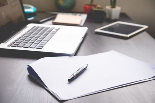 Blank Papers with pen,tablet and laptop on   the desk.