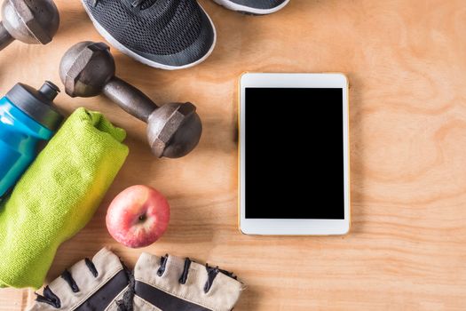Top view of Tablet with Sport stuff on wooden table background, Fitness lifestyle concept