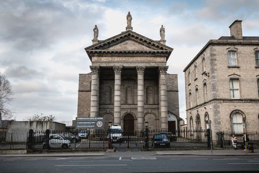 Dublin, Ireland - February 13, 2019: Street atmosphere and architecture of St. Audoen's Roman Catholic Church that people visit on a winter day