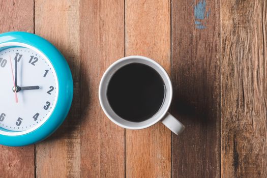 Top view of Coffee cup with clock on wooden table background.