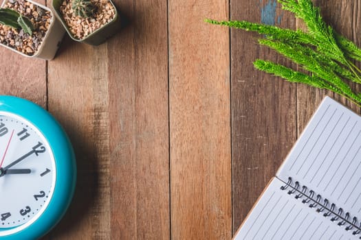 Top view of Blank notebook with clock,paddy rice and cactus on wooden table background. Free space for text