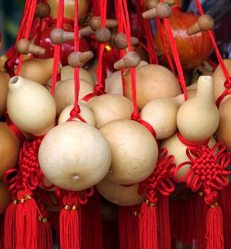 An outdoor vendor sells dried bottle gourds that are decorated with red ribbons
