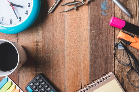 Top view of Coffee cup with clock,glasses and  Office supplies on wooden table background. Free space for text