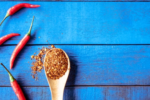 Top view of Red hot chilli peppers with cayenne on blue wooden table background, Free space for text