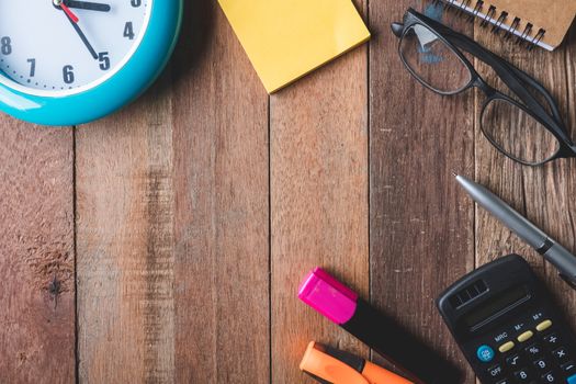 Top view of  Office supplies with clock and glasses on wooden table background. Free space for text