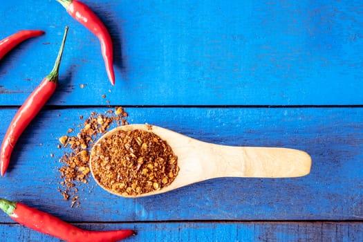 Top view of Red hot chilli peppers with cayenne on blue wooden table background, Free space for text