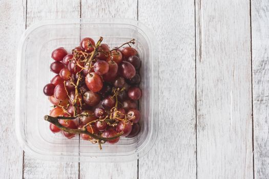 Top view of Red grapes on white wooden table background.