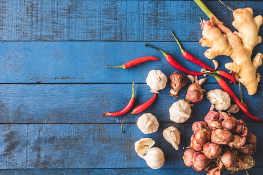 Top view of  Red onion with Garlic, Red hot chilli peppers and Gingers on blue wooden table background.