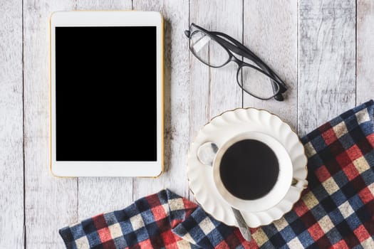 Top view of Coffee cup with tablecloth, tablet and glasses on wooden table background