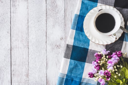 Top view of Coffee cup with flowers and tablecloth on wooden table background, Free space for text
