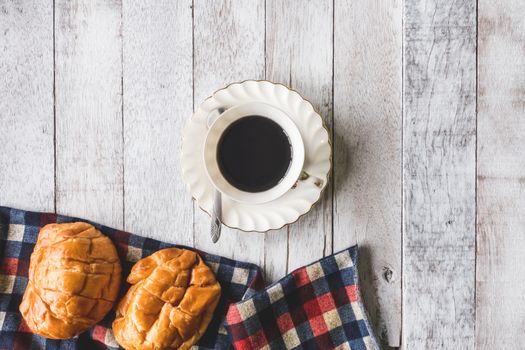Top view of Coffee cup with bread and tablecloth on wooden table background