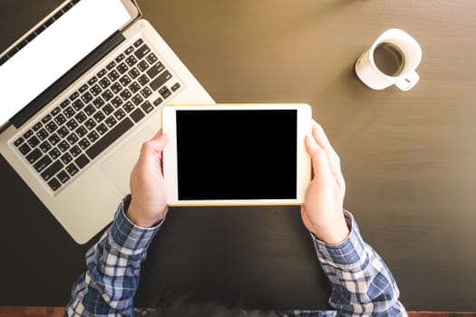 Top view of Male hands using Tablet, Laptop with Cup of coffee on the desk.