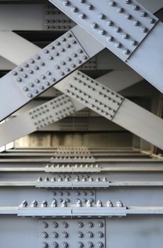The underside of a bridge with large steel girders, bolts and nuts