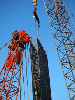A construction site with two cranes and building elements
