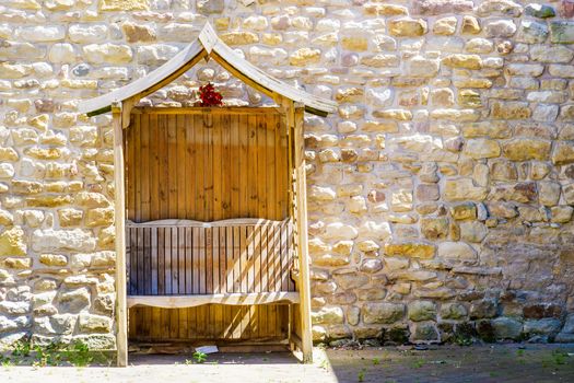 Wooden arbour in car park against a wall UK